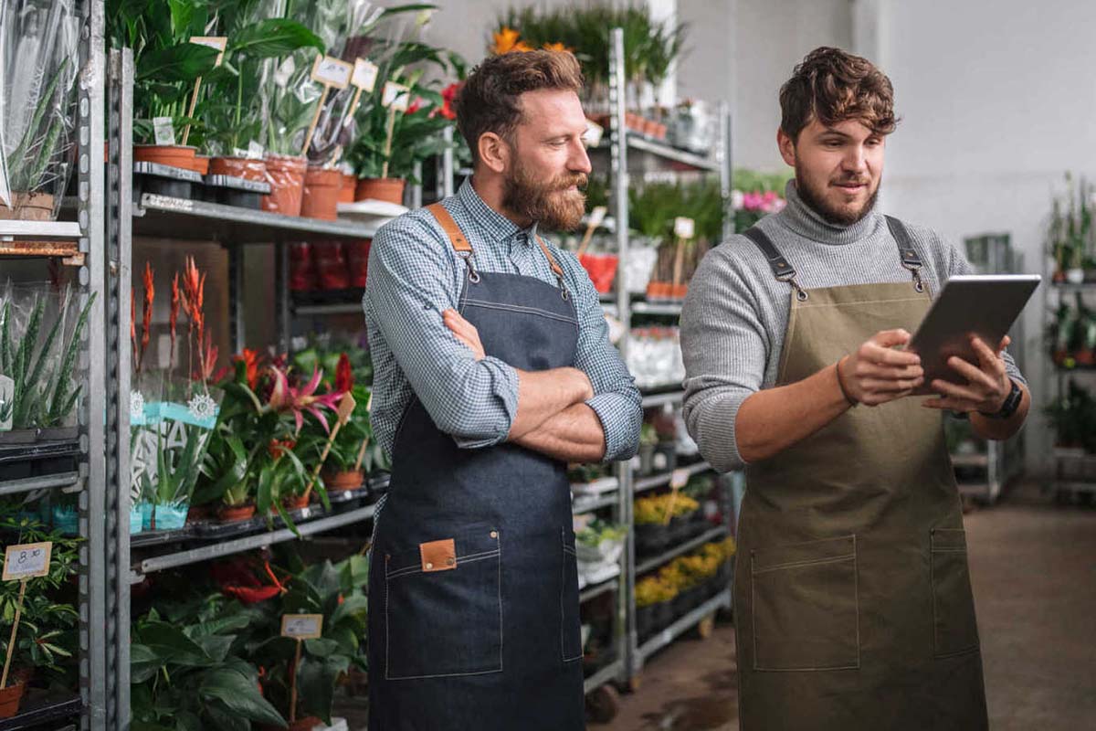 Two men in front of cc carts filled with potted plants