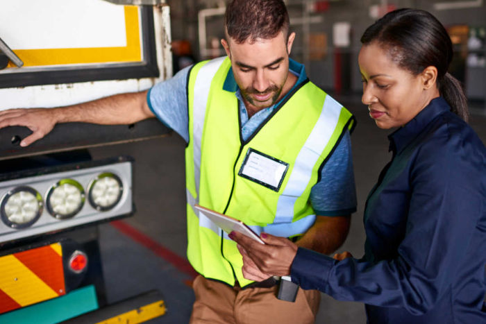 Truck driver and colleague looking a tablet