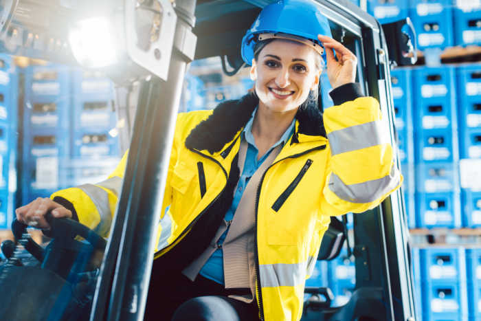 Woman on forklift in drinks warehouse