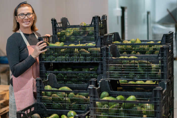 Woman with crates full of avocado's in a workspace